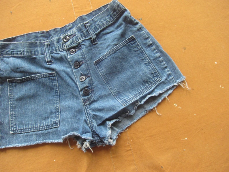 Op de afbeelding: Een lichtblauwe denim short met rafelige randen. De short heeft een knoopsluiting en meerdere zakken.
