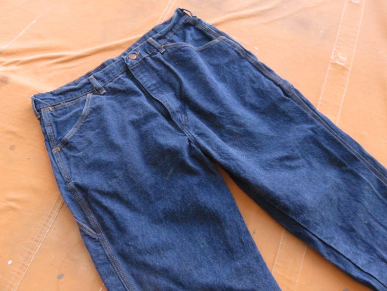 May include: A pair of dark blue denim work trousers with reinforced seams and pockets.