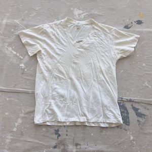 May include: A plain white v-neck t-shirt with a slightly wrinkled texture.