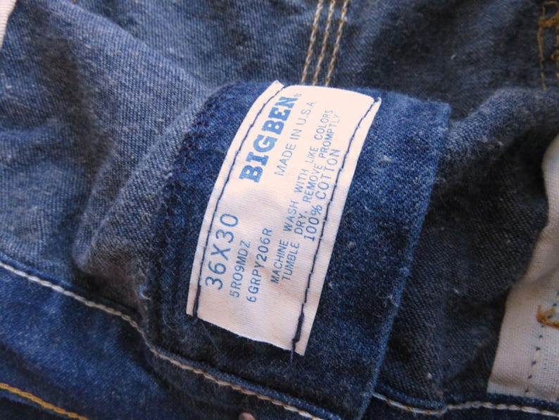 May include: A close-up of a blue denim jean label with the text "BIGBEN" and the size "36X30". The label also includes care instructions: "Machine wash with like colours, tumble dry, remove promptly, 100% cotton, Made in USA".