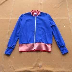 May include: A blue and red striped bomber jacket with a white zipper. The jacket has a ribbed collar and cuffs.