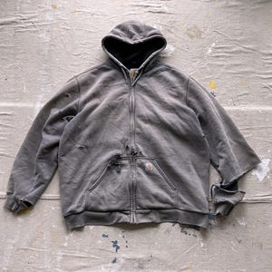 May include: A gray hooded sweatshirt with a zipper closure and a small pocket on the left chest. The sweatshirt has a distressed look with some rips and tears.