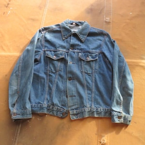 May include: A blue denim jacket with a button closure, two chest pockets, and two front pockets.
