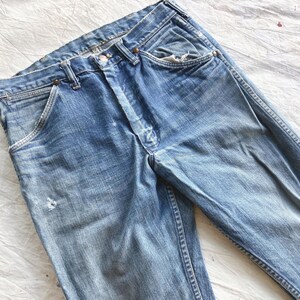 Peut inclure: Jean en denim bleu d&eacute;lav&eacute; avec une conception classique &agrave; cinq poches. Le jean pr&eacute;sente des signes d'usure, notamment des zones ab&icirc;m&eacute;es et un aspect us&eacute;. La couleur bleu clair est uniforme sur tout le v&ecirc;tement.