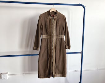 May include: A brown long-sleeved dress with a high collar and a full-length zip. The dress has gold-coloured embroidery along the zip, waist, and cuffs. It is hanging on a blue metal rail.