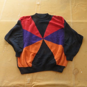 May include: A black sweater with a geometric pattern in red, orange, and purple.