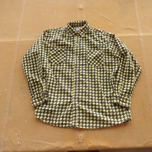 Könnte beinhalten: Ein langärmliges Hemd mit Knöpfen und einem karierten Muster in Schwarz und Gelb.