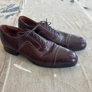 May include: A pair of dark brown leather lace-up shoes with a cap toe design.