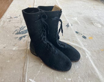 May include: A pair of black felt boots with lace-up closures. The boots have a rounded toe and a low heel.