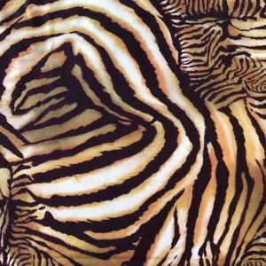 May include: A close-up of a fabric with a zebra print pattern. The fabric is brown, black, and white with a swirl design.