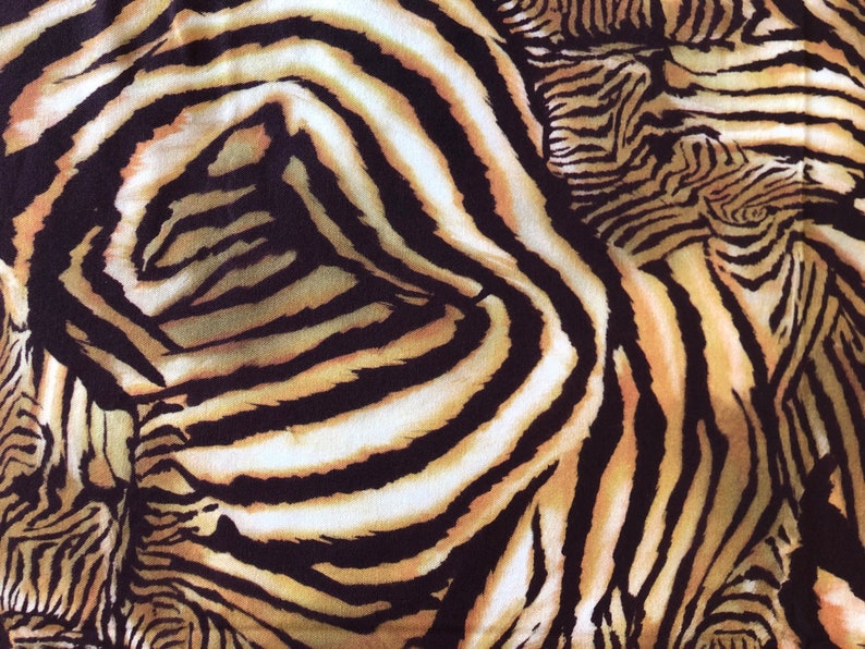 May include: A close-up of a fabric with a zebra print pattern. The fabric is brown, black, and white with a swirl design.