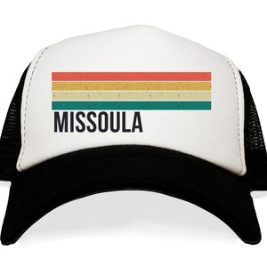 May include: A white and black trucker hat with a vintage-style rainbow stripe and the text "MISSOULA" in black.