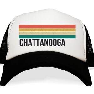 May include: White trucker hat with a black mesh back. The front of the hat features a vintage-style rainbow stripe design and the text "CHATTANOOGA" in black.
