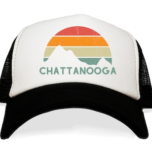 May include: A white and black trucker hat with a retro sunset graphic and the text "CHATTANOOGA" in green.