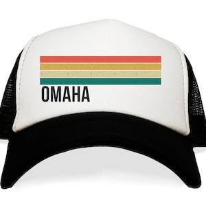 May include: A white and black trucker hat with a retro-style striped design in red, orange, yellow, and green. The hat has the word "OMAHA" printed in black on the front.