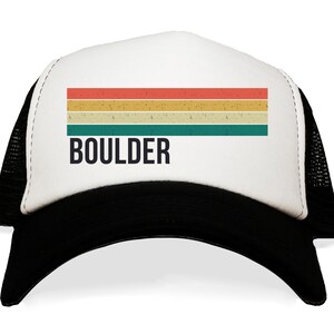 May include: A white and black trucker hat with a vintage-style rainbow stripe design and the word "BOULDER" in black text.