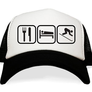 May include: A white and black trucker hat with a black mesh back. The front of the hat has three black squares with white icons. The icons are a fork and knife, a bed, and a skier.