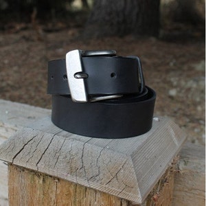 May include: A black leather belt with a silver buckle. The belt is folded in half and the buckle is visible.