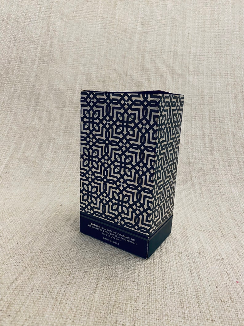 Puede incluir: Una caja con un patr&oacute;n en blanco y negro con el texto "CONTAINS: 50 ALCOHOL, W.C. FRAGRANCE, BHT, BENZYL SALICYLATE, PARFUM, CI 15985, CI 19140, CI 14700, YELLOW NO. 5, CI 15850, RED NO. 4, MADE IN FRANCE".