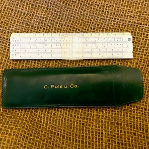May include: A vintage slide rule in a green leather case with the inscription "C. Puls u. Co."