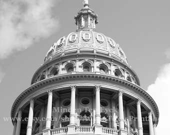 May include: Black and white photograph of a domed building with classical architecture. The building features a series of columns, arched windows, and a statue atop the dome. The sky is visible in the background.