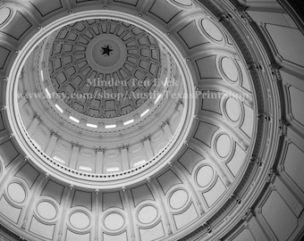 May include: Black and white photograph of the interior of a domed building. The dome is made of white stone and has a circular pattern of decorative elements. The photograph is taken from the bottom of the dome, looking up.