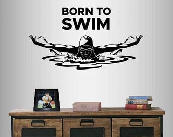 May include: Black and white wall decal of a swimmer with the text "Born to Swim". The decal is on a white wall above a wooden dresser with drawers.