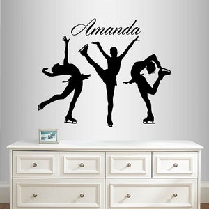 May include: Black silhouette wall decal of three figure skaters with the name "Amanda" above them. The decal is on a white wall above a white dresser with six drawers.