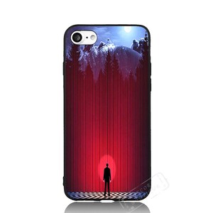 May include: A black phone case with a red and blue image of a silhouette of a person standing in front of a red curtain with a mountain scene in the background.
