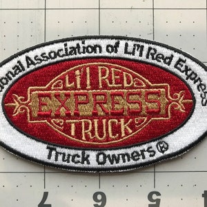 Op de afbeelding: Witte en rode geborduurde patch met de tekst "National Association of Lil' Red Express Truck Owners®" en "Lil' Red Express Truck" in een gouden lettertype.