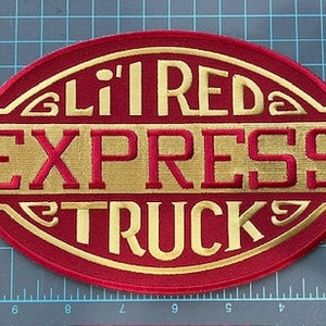 以下が含まれることがあります： 「Li'l RED EXPRESS TRUCK」の文字が入った赤と金の刺繍パッチ。パッチには装飾的な縁取りがあり、丸みを帯びた端を持つ長方形です。テキストは太字で様式化されたフォントです。