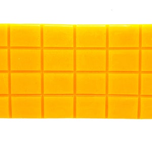 Pu&ograve; includere: Un blocco di cera giallo con un motivo a griglia, diviso in 18 quadrati.