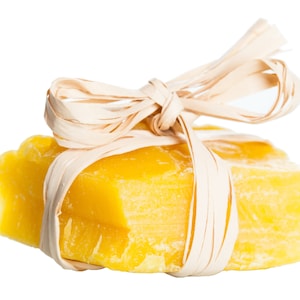 Könnte beinhalten: Eine gelbe Seifenstange, die mit einem natürlichen Bastband mit Schleife gebunden ist.