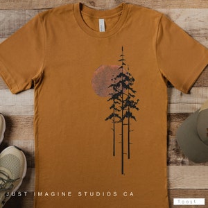 May include: A mustard yellow t-shirt with a black silhouette of three pine trees and a large orange sun behind them. The text "Just Imagine Studios CA" is printed at the bottom of the shirt.