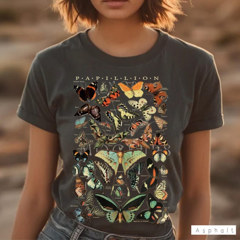 May include: Dark gray t-shirt featuring a detailed illustration of various butterfly species. The design includes the word "Papillon" at the top, with a variety of colorful butterflies in different shapes and sizes. The shirt is a casual style.