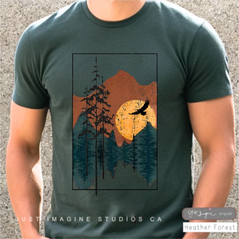 May include: A green t-shirt with a vintage-style graphic of a forest scene with a sunset and a bird flying over the trees. The text "Just Imagine Studios CA" is at the bottom of the shirt.