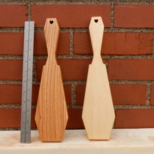 Puede incluir: Dos esp&aacute;tulas de madera con recortes en forma de coraz&oacute;n en la parte superior. Una esp&aacute;tula es de color marr&oacute;n claro y la otra es de color madera natural.
