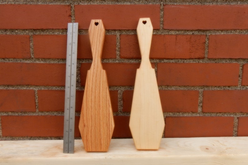 Puede incluir: Dos esp&aacute;tulas de madera con recortes en forma de coraz&oacute;n en la parte superior. Una esp&aacute;tula es de color marr&oacute;n claro y la otra es de color madera natural.
