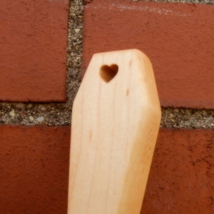 Puede incluir: Una cuchara de madera con un corte en forma de coraz&oacute;n. La cuchara es de color marr&oacute;n claro y tiene un acabado liso.