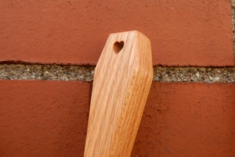 Puede incluir: Una cuchara de madera con un corte en forma de coraz&oacute;n en el extremo del mango.