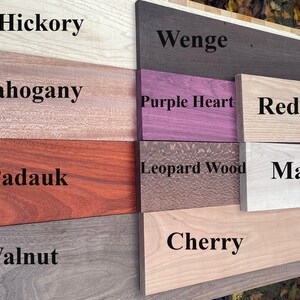 May include: Close-up of eight different wood samples, labeled with their names: Hickory, Wenge, Purple Heart, Red Oak, Maple, Leopard Wood, Cherry, and Walnut.