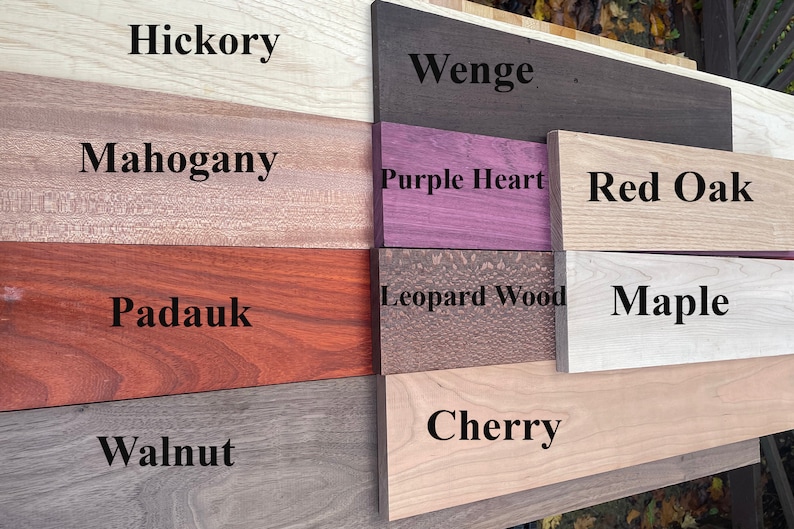May include: Close-up of eight different wood samples, labeled with their names: Hickory, Wenge, Purple Heart, Red Oak, Maple, Leopard Wood, Cherry, and Walnut.