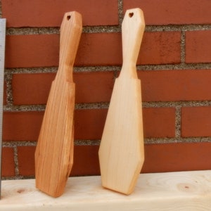 Puede incluir: Dos esp&aacute;tulas de madera con recortes en forma de coraz&oacute;n en la parte superior. La esp&aacute;tula de la izquierda es de un color de madera m&aacute;s oscuro, mientras que la esp&aacute;tula de la derecha es de un color de madera m&aacute;s claro.