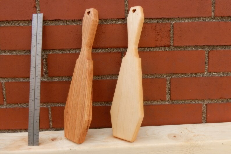 Puede incluir: Dos esp&aacute;tulas de madera con recortes en forma de coraz&oacute;n en la parte superior. La esp&aacute;tula de la izquierda es de un color de madera m&aacute;s oscuro, mientras que la esp&aacute;tula de la derecha es de un color de madera m&aacute;s claro.