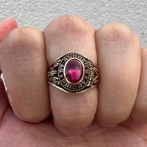 May include: A gold class ring with a red stone and the inscription "St. Andrew's Priory" around the band.