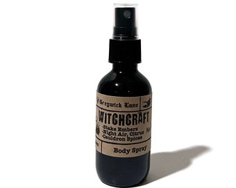 Peut inclure: Un flacon de vaporisateur corporel en verre noir avec un pulvérisateur noir. L'étiquette indique "Witchcraft" avec des notes de parfum. Le flacon est sur fond blanc.