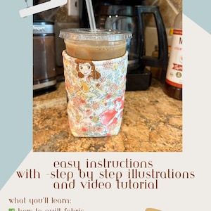 May include: A floral fabric cup sleeve-koozie featuring Disney princesses Belle and Ariel. The koozie is wrapped around a clear plastic cup with a straw. Text on the image reads "easy instructions with step by step illustrations and video tutorial."