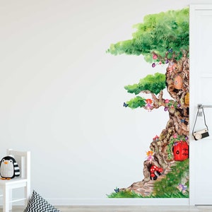 Op de afbeelding: Een muursticker in aquarelstijl met een grote boom met een fantasierijk feeënhuis in de stam. De boom heeft groene bladeren en een bruine stam met een rode deur. Er zijn kleine feeën en vlinders rond de boom verspreid.