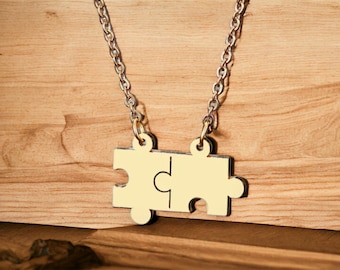 May include: A gold chain necklace with a pendant shaped like two interlocking puzzle pieces.