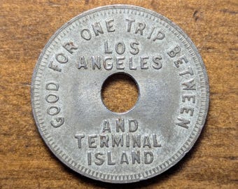 May include: A silver token with the text "Good for one trip between Los Angeles and Terminal Island" around the edge.